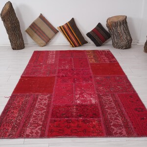 K&ouml;nnte beinhalten: Ein roter Patchwork-Teppich mit verschiedenen Mustern und Texturen. Der Teppich ist aus recycelten Materialien hergestellt und hat ein einzigartiges, handgemachtes Aussehen.