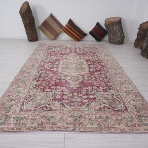 May include: A vintage rug with a pink and cream color scheme. The rug has a floral pattern with a central medallion. The rug is in good condition with some wear and tear.