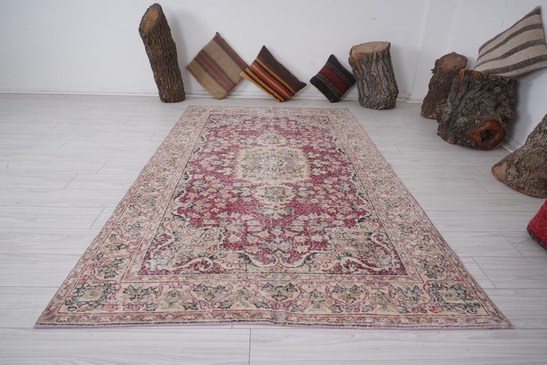 May include: A vintage rug with a pink and cream color scheme. The rug has a floral pattern with a central medallion. The rug is in good condition with some wear and tear.