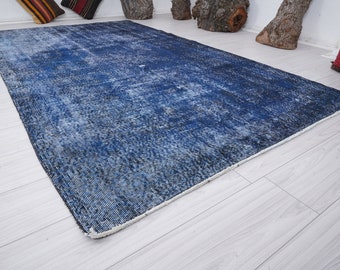 May include: A blue and white distressed vintage rug with a faded pattern. The rug has a white fringe border.