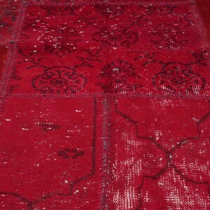 K&ouml;nnte beinhalten: Ein roter Patchwork-Teppich mit einem abgenutzten, Vintage-Look. Der Teppich besteht aus verschiedenen Stoffst&uuml;cken, die zusammengen&auml;ht wurden und ein einzigartiges und interessantes Muster bilden.