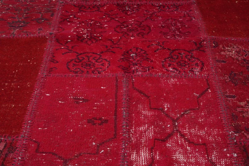 K&ouml;nnte beinhalten: Ein roter Patchwork-Teppich mit einem abgenutzten, Vintage-Look. Der Teppich besteht aus verschiedenen Stoffst&uuml;cken, die zusammengen&auml;ht wurden und ein einzigartiges und interessantes Muster bilden.