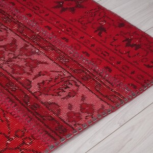 K&ouml;nnte beinhalten: Nahaufnahme eines roten und rosafarbenen Teppichs mit Fransen. Der Teppich hat ein traditionelles Design mit floralen Motiven.