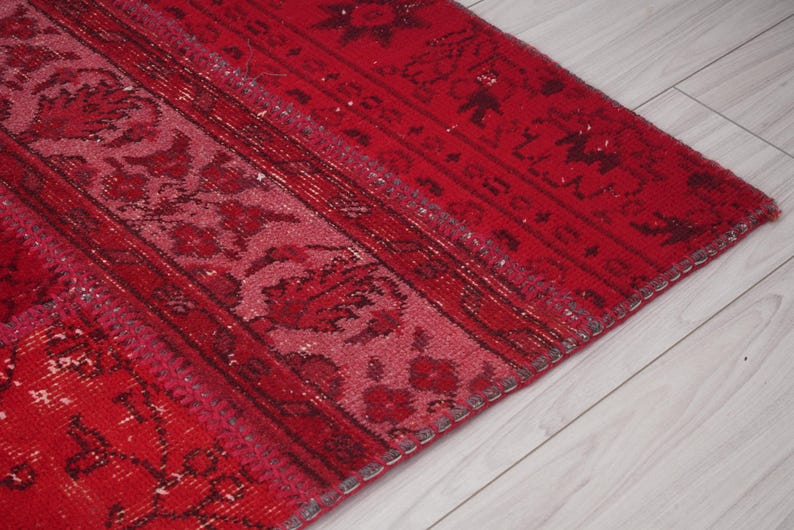 K&ouml;nnte beinhalten: Nahaufnahme eines roten und rosafarbenen Teppichs mit Fransen. Der Teppich hat ein traditionelles Design mit floralen Motiven.