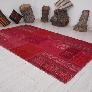 K&ouml;nnte beinhalten: Ein roter Patchwork-Teppich mit verschiedenen Mustern und Texturen. Der Teppich ist aus recycelten Materialien hergestellt und perfekt, um jedem Raum einen Hauch von Boho-Stil zu verleihen.