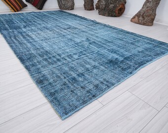 May include: A blue distressed rug with a subtle pattern. The rug is made of a soft, woven material and has a fringed edge.