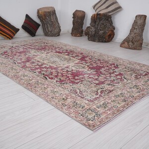 May include: A vintage rug with a pink and cream floral pattern. The rug has a distressed look and is perfect for adding a touch of bohemian style to any room.