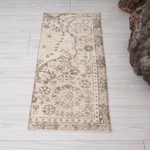 May include: A rectangular, vintage-style rug with a beige background and intricate floral patterns in shades of brown, green, and cream. The rug has a detailed border and is placed on a light-colored wooden floor.