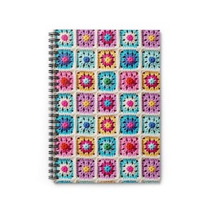 May include: A spiral bound notebook with a colorful crocheted design on the cover. The design features a variety of squares in shades of pink, blue, yellow, and green.