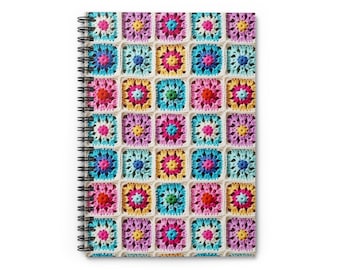 Pode incluir: Um caderno de espiral com um design de crochê colorido na capa. O design apresenta uma variedade de quadrados em tons de rosa, azul, amarelo e verde.
