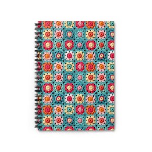 May include: A spiral bound notebook with a colorful crocheted pattern on the cover. The pattern features squares of different colors, including pink, orange, yellow, and blue, on a teal background.