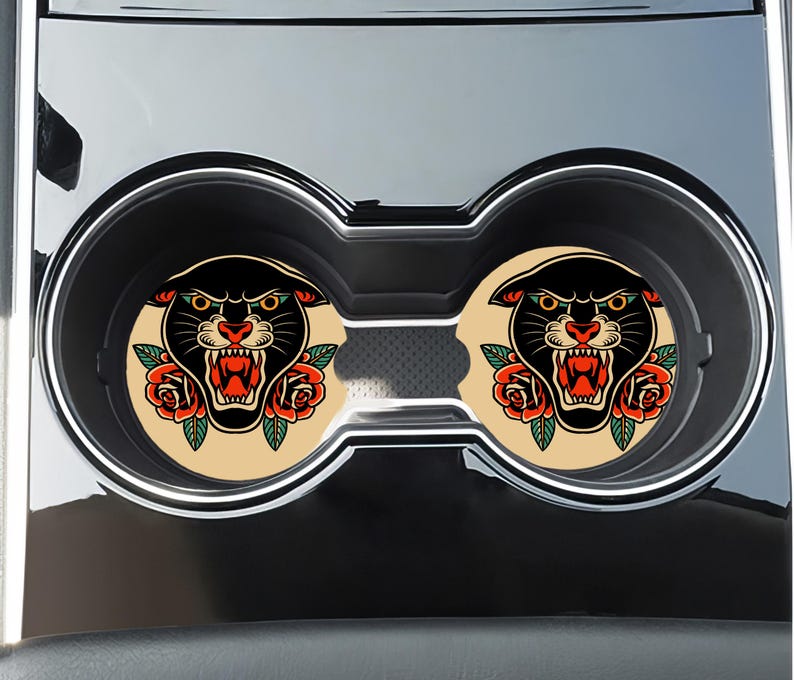 May include: Two black panther head car coasters with red roses and a vintage tattoo style. The coasters are beige with a black outline.