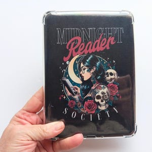 K&ouml;nnte beinhalten: Eine transparente Schutzh&uuml;lle mit einem schwarzen Grafikdesign. Das Design zeigt die Worte "MIDNIGHT Reader SOCIETY", eine lesende Frau, einen Mond, Rosen und Totenk&ouml;pfe. Die H&uuml;lle wird in einer Hand gehalten.