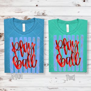 May include: Two t-shirts, one aqua and one teal, each with the words "Play Ball" in red script. The shirts have a crew neck and a design of blue vertical stripes with gold accents.