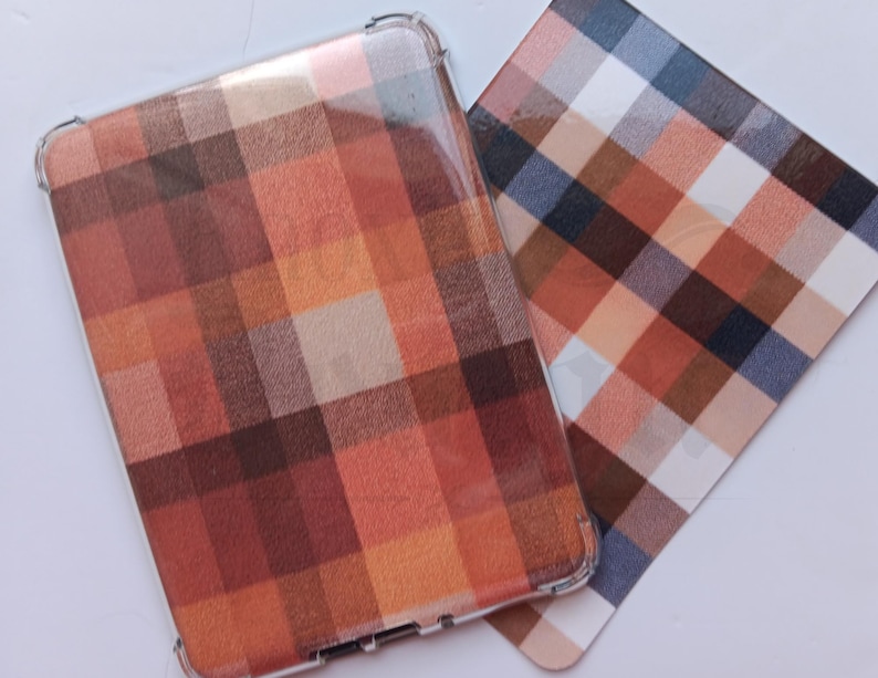May include: A clear protective case and a matching card display a plaid pattern in shades of brown, orange, and white. The case is for a rectangular device, the card is a flat square.