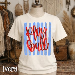Bella Canvas brand ivory color tshirt with play ball graphic in red and gold with blue stripes