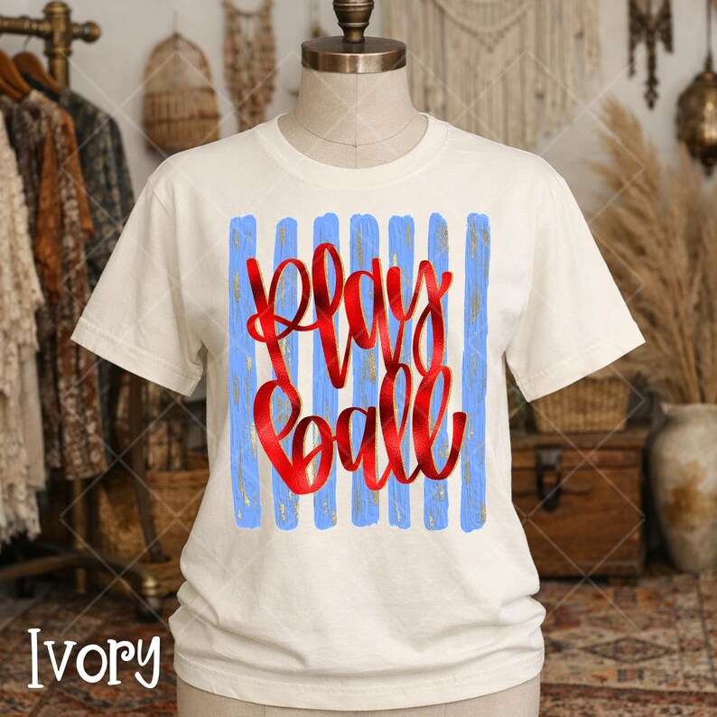 Bella Canvas brand ivory color tshirt with play ball graphic in red and gold with blue stripes