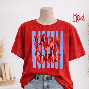 May include: A red t-shirt with a blue and white design. The design features the words "Play Ball" in a cursive font. The shirt is made of a soft material and has a relaxed fit.