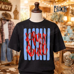 May include: Black t-shirt with the words "Play Ball" in red script. The design features vertical light blue stripes. The shirt is displayed on a mannequin.