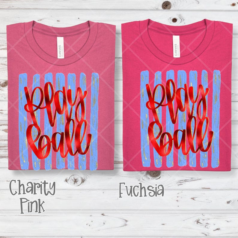 May include: Two pink t-shirts with the words "Play Ball" in red script over blue vertical stripes. The shirt on the left is "Charity Pink" and the shirt on the right is "Fuchsia". Both shirts have a crew neck.