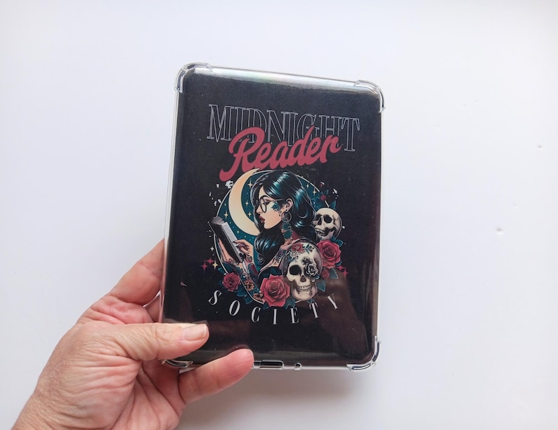K&ouml;nnte beinhalten: Eine schwarze Tablet-H&uuml;lle mit einem Design, das eine lesende Frau, Totenk&ouml;pfe, Rosen und die Worte "Midnight Reader Society" zeigt. Die H&uuml;lle befindet sich in einer transparenten Schutzh&uuml;lle.