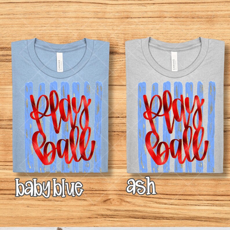May include: Two t-shirts, one baby blue and one ash, with the words "Play Ball" in red script. The text is superimposed on a blue and gold striped design. The baby blue shirt has the words "baby blue" below it.