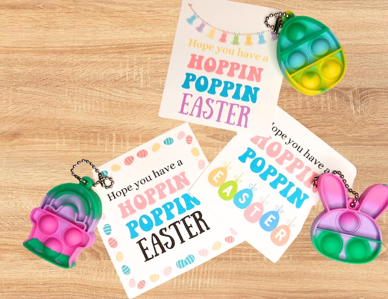 May include: Three Easter-themed cards with the text "Hope you have a Hoppin Poppin Easter" and three colorful pop-it fidget toys shaped like an egg, a bunny, and a rainbow.