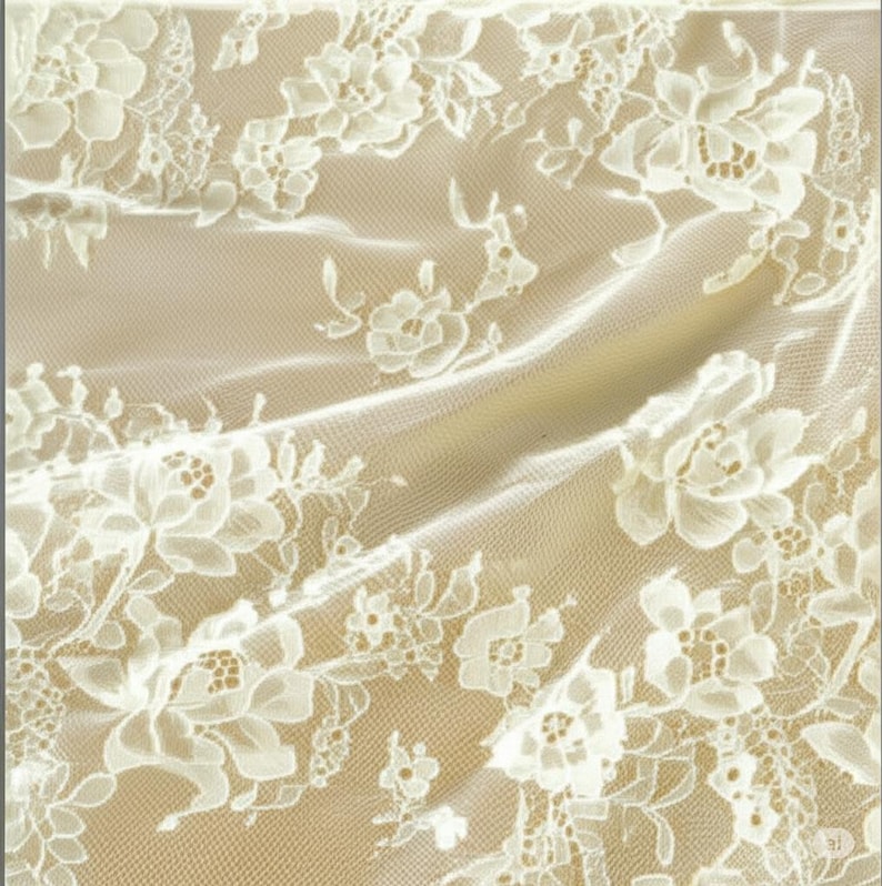May include: Ivory lace fabric with a floral pattern. The delicate lace features detailed white flowers and leaves against a beige background. The fabric is draped, creating soft folds and shadows, highlighting the intricate design.