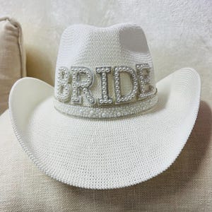May include: White cowboy hat with a pearl embellished "BRIDE" band.