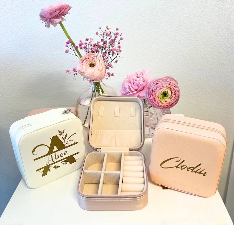 Pode incluir: Tr&ecirc;s caixas de joias cor-de-rosa com letras douradas. As caixas s&atilde;o personalizadas com os nomes "Alice", "Clodin" e uma &uacute;nica inicial "A".