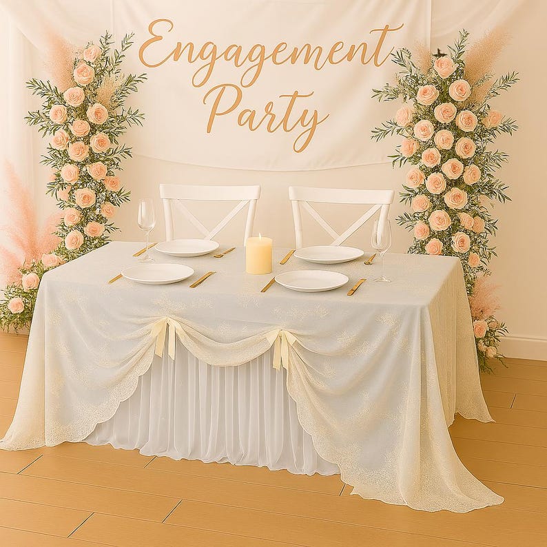May include: A decorated table set for an engagement party. The table is covered with a light blue tablecloth and a white skirt. The banner above reads "Engagement Party". Floral arrangements and candles complete the setting.