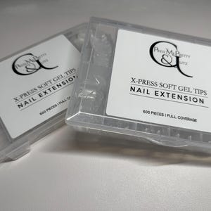 May include: Two clear plastic containers of nail extension tips. Each container has a white label with black text that reads "X-PRESS SOFT GEL TIPS NAIL EXTENSION" and "600 Pieces | Full Coverage". The brand logo is also visible.