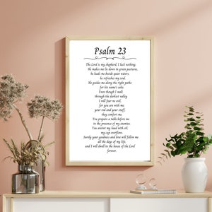 Peut inclure: Une impression d'art murale encadrée présentant le texte du Psaume 23 en police serif noire sur fond blanc. L'impression est insérée dans un cadre en bois clair et affiche le passage biblique complet commençant par le titre Psaume 23.