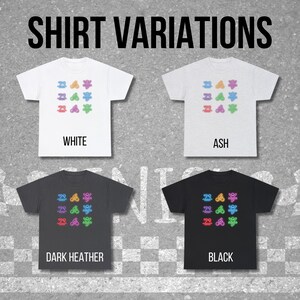 以下が含まれることがあります： 白、アッシュ、ダークヘザー、黒の4色のTシャツ。それぞれ、カラフルな抽象的な形の繰り返し模様がプリントされています。「SHIRT VARIATIONS」の文字が上にあり、各シャツの下に色の名前が書かれています。
