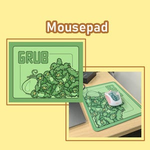 May include: Green mousepad with a cartoon design featuring the word "GRUB" and a pile of green creatures. The mousepad is rectangular and has a light green border. A computer mouse is on the mousepad.