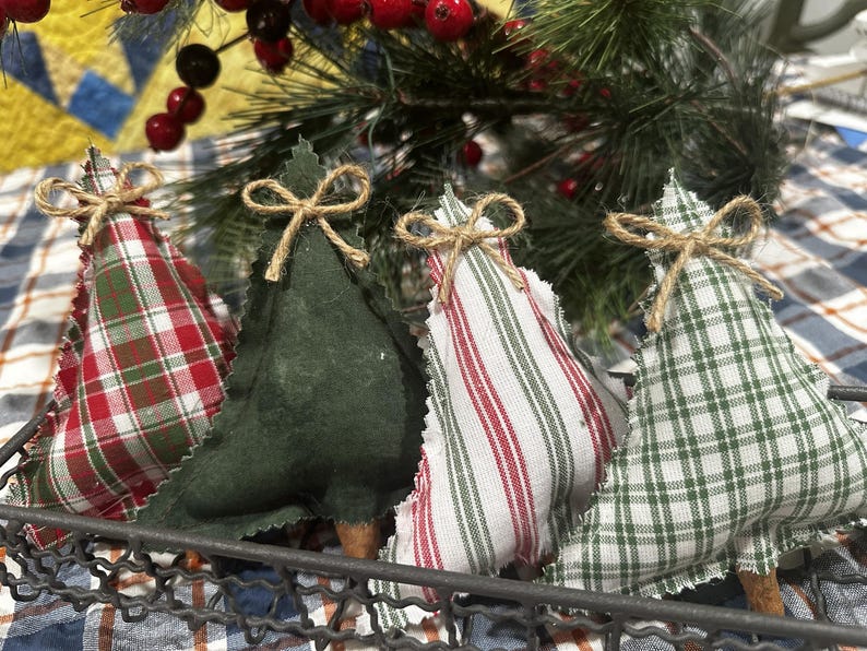 Pu&ograve; includere: Quattro decorazioni natalizie a forma di albero in tessuto all'interno di un cestino in filo metallico. Ogni albero presenta un motivo diverso: tartan rosso e verde, verde scuro tinta unita, bianco a righe rosse e bianco a quadri verdi.