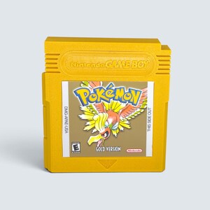 Peut inclure: Une cartouche de jeu vidéo jaune Nintendo Game Boy pour Pokémon Version Or. L'étiquette présente le Pokémon Ho-Oh, le texte Pokémon Gold Version, le logo Nintendo et une classification ESRB E. Le boîtier est gravé Nintendo GAME BOY.