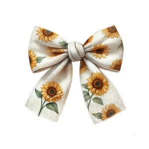 May include: A cream-coloured bow decorated with a sunflower pattern. The bow features yellow and brown sunflowers and green leaves. The bow is tied in the centre and has two long, flowing tails.