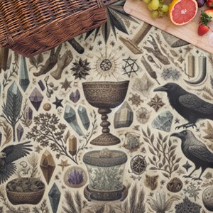 Puede incluir: Escena de picnic con una cesta de mimbre, una tabla de cortar de madera con uvas, pomelo y fresas, y una manta estampada con cristales, cuervos y elementos místicos.