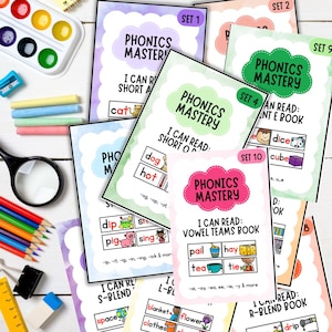 May include: A collection of colorful phonics flashcards with the title "Phonics Mastery". The cards feature words and illustrations for early reading skills, including short vowels, blends, and vowel teams. Educational supplies like crayons and a magnifying glass are also visible.