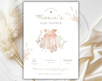 May include: A baby shower invitation with a watercolor design. The invitation features the text "Rosie's BABY SHOWER" in elegant script, along with details for the event. The design includes a dress, shoes, and floral accents in soft peach and green hues.