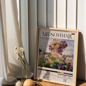 May include: A framed movie poster for the 2019 film "Midsommar" directed by Ari Aster. The poster features a woman wearing a flower crown and a floral dress. The poster also includes the film's title, director, and release date.