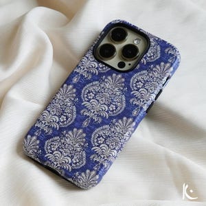 May include: A blue phone case with a white floral pattern. The case has a black camera bump with three lenses.