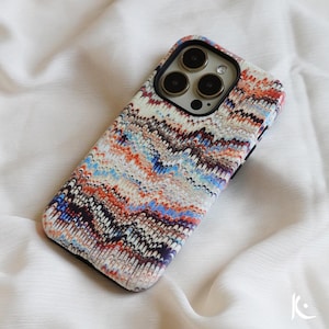 May include: A colorful phone case with a marbled pattern in shades of blue, red, white, and black. The case has a raised camera bump with three black camera lenses.