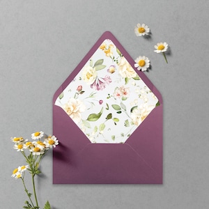 May include: A mauve envelope with a floral pattern on the inside flap. The pattern features white, yellow, and pink flowers with green leaves on a light blue background.