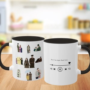 Könnte beinhalten: Zwei weiße Kaffeetassen mit schwarzen Henkeln und schwarzen Rändern. Eine Tasse zeigt ein Design mit Comicfiguren aus dem koreanischen Drama "Here I Am Again". Die andere Tasse hat ein Musikplayer-Design mit dem Text "Here I Am Again | Baek Yerin" und einem Herz-Symbol.