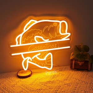 May include: A neon sign shaped like a fish with the name "Cosentinos" written on it. The sign is lit up and glowing orange.