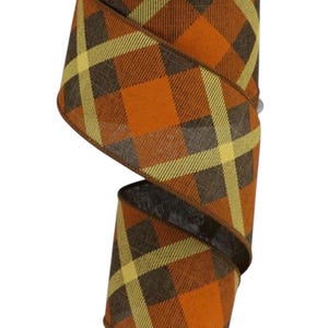 May include: A spool of decorative ribbon with a plaid pattern in shades of orange, brown, and yellow. The ribbon is ideal for crafts, gift wrapping, or seasonal decor. The spool has a white core.