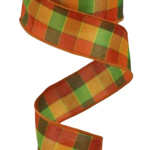 May include: A spool of decorative ribbon with a plaid pattern in fall colors. The ribbon features a repeating pattern of orange, yellow, green, and brown squares. The ribbon is ideal for crafts and gift wrapping.