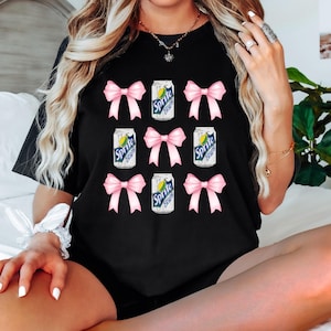 May include: Black t-shirt with a repeated pattern of pink bows and cans of Sprite.
